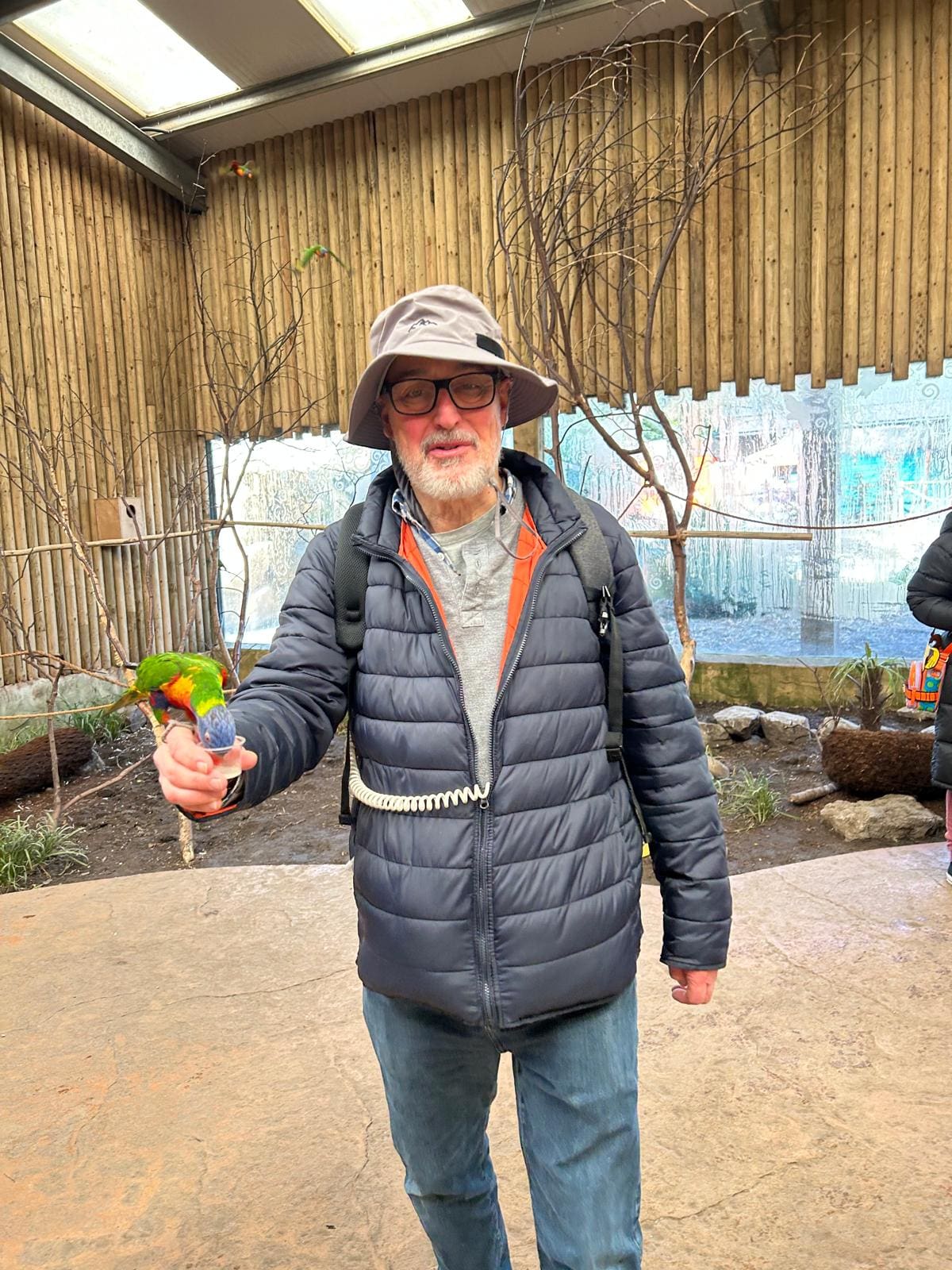 Nigel holding a parrot while wearing the Optune device