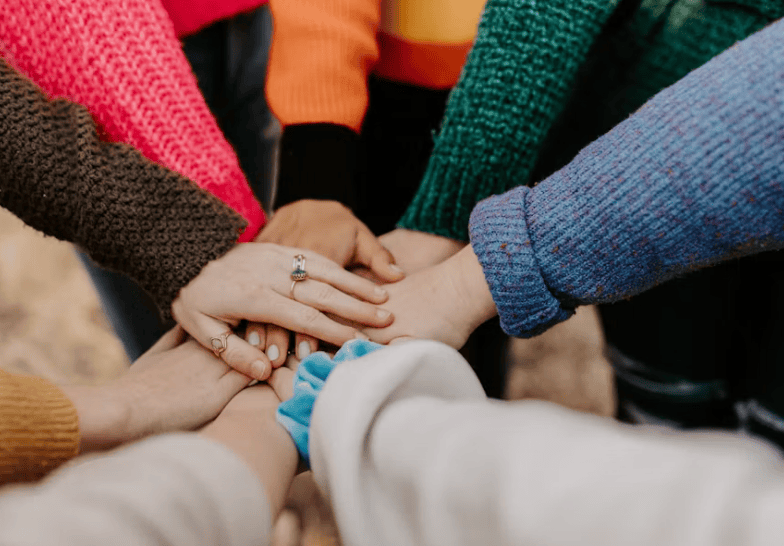 Group of people placing their hands together in a show of support